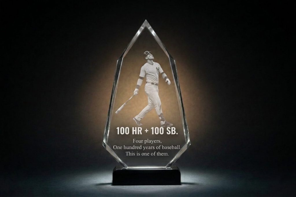 Crystal Sensations custom diamond-shaped crystal award with 2D surface laser engraving — baseball player in ball-watch pose after home run, bold "100 HR + 100 SB" milestone text, on black base with clear bevelled edges