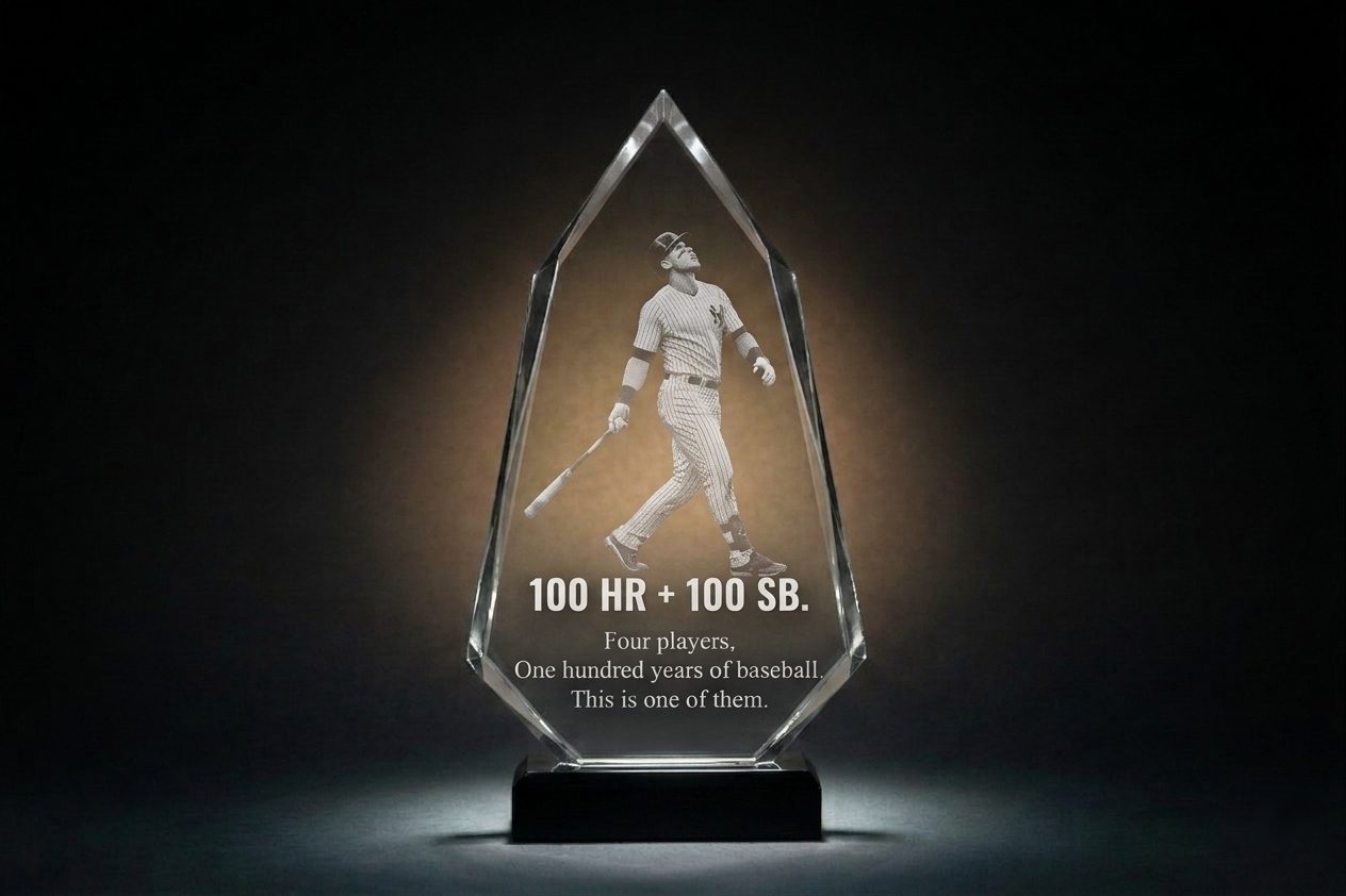 Crystal Sensations custom diamond-shaped crystal award with 2D surface laser engraving — baseball player in ball-watch pose after home run, bold "100 HR + 100 SB" milestone text, on black base with clear bevelled edges