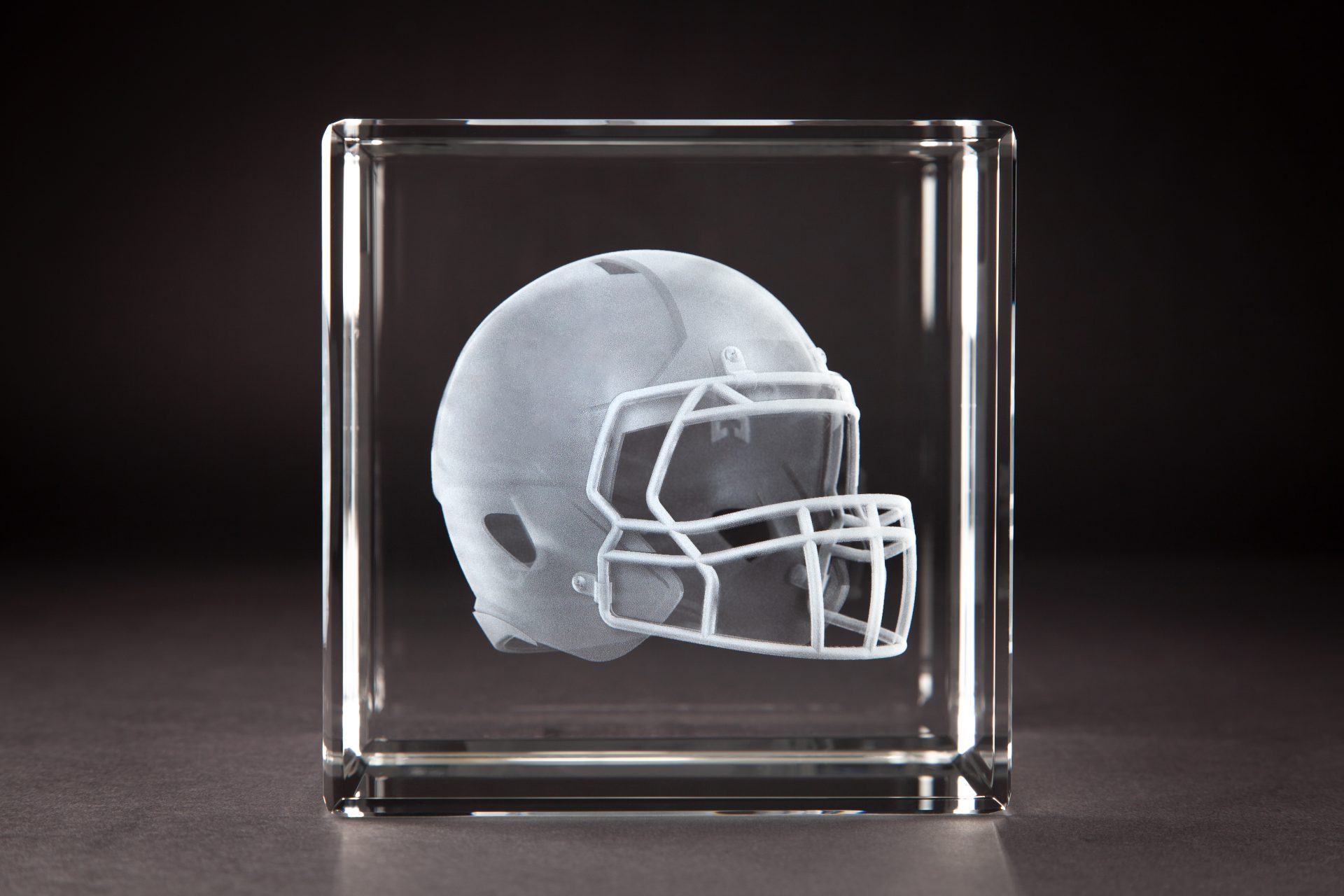 Crystal Sensations 3D laser engraved crystal cube featuring a detailed football helmet suspended inside optical crystal — custom sports crystal trophies by Crystal Sensations