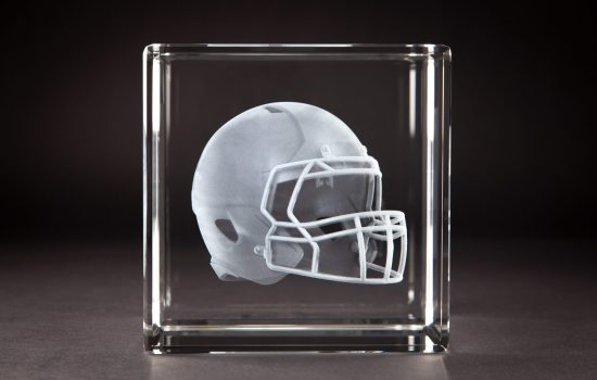 Crystal Sensations 3D laser engraved crystal cube featuring a detailed football helmet suspended inside optical crystal — custom sports crystal trophies by Crystal Sensations